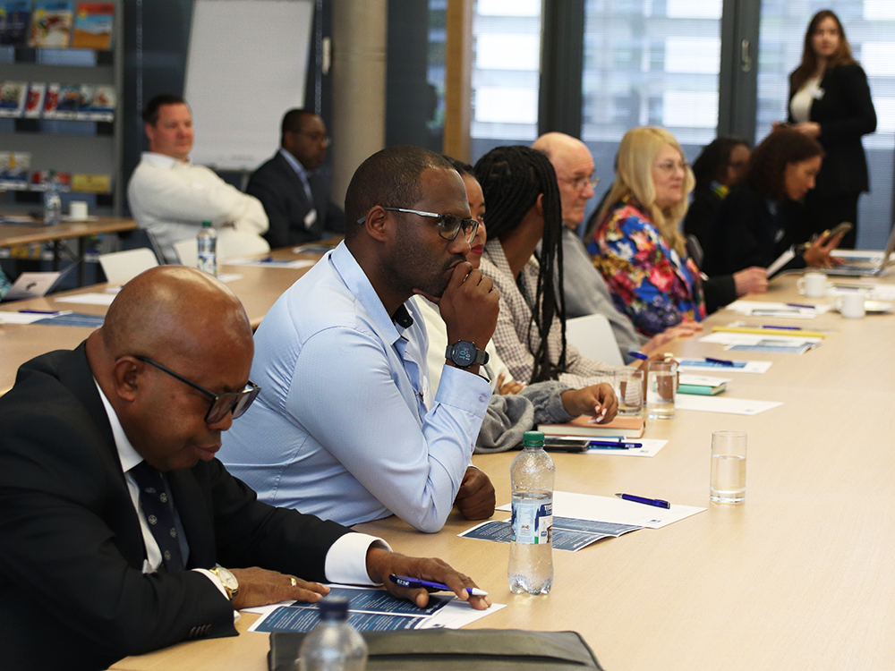 People sitting in rows. listening and taking notes during a DBA Research Workshop
