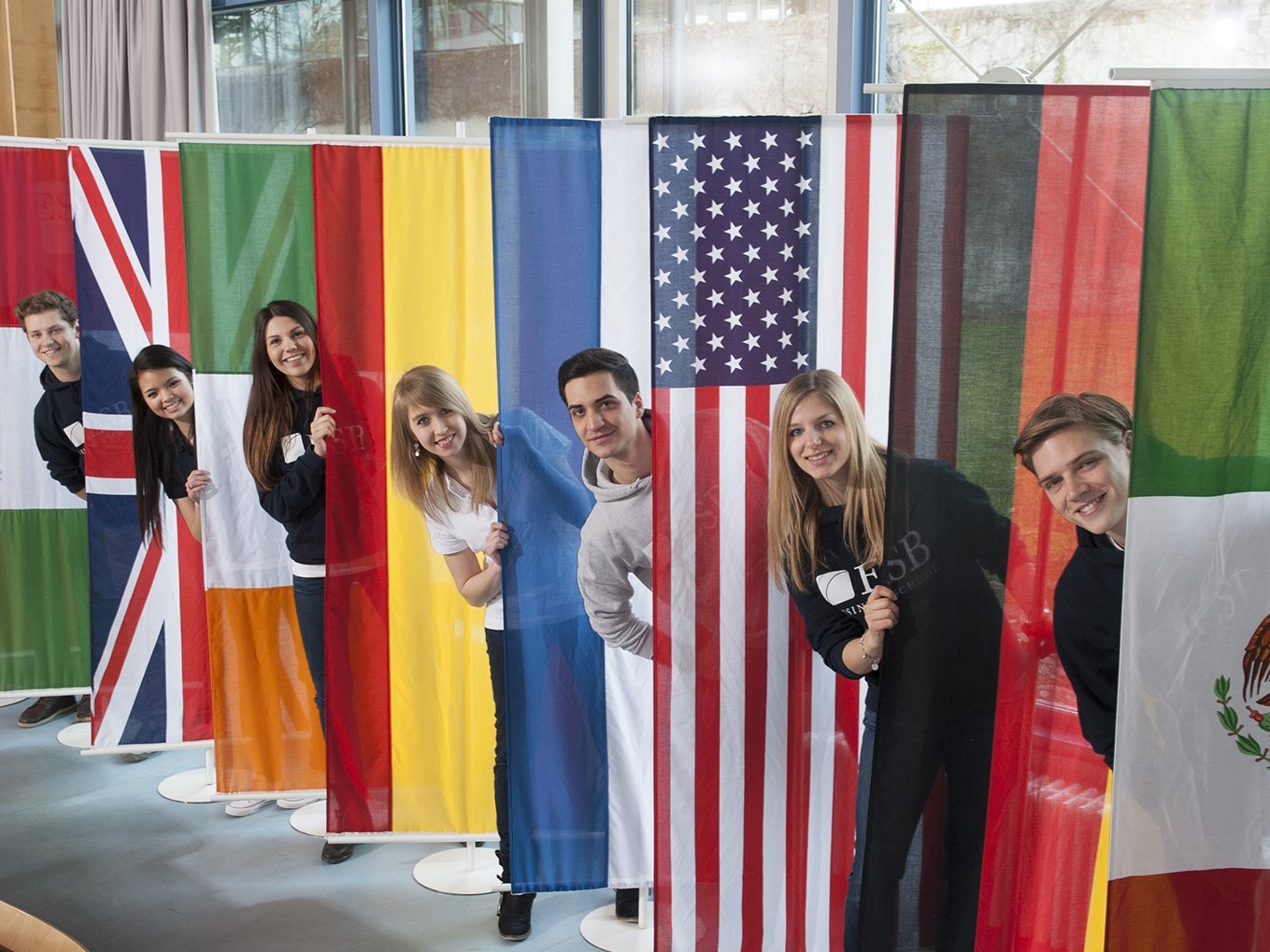 Students posing behind the flags of countries of the partner universities of ESB Business School.