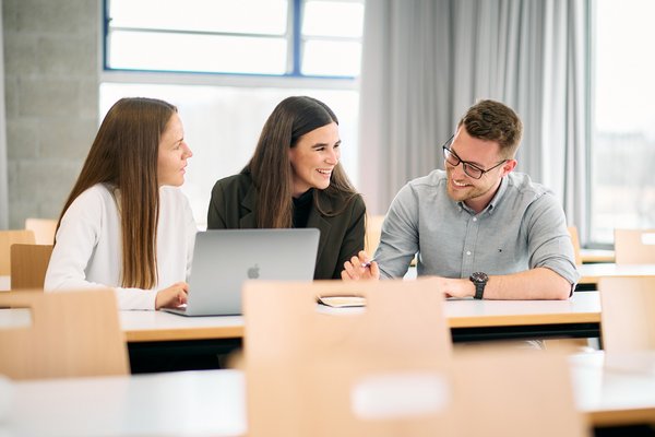 Master students at the ESB Business School chatting in a lecture room.