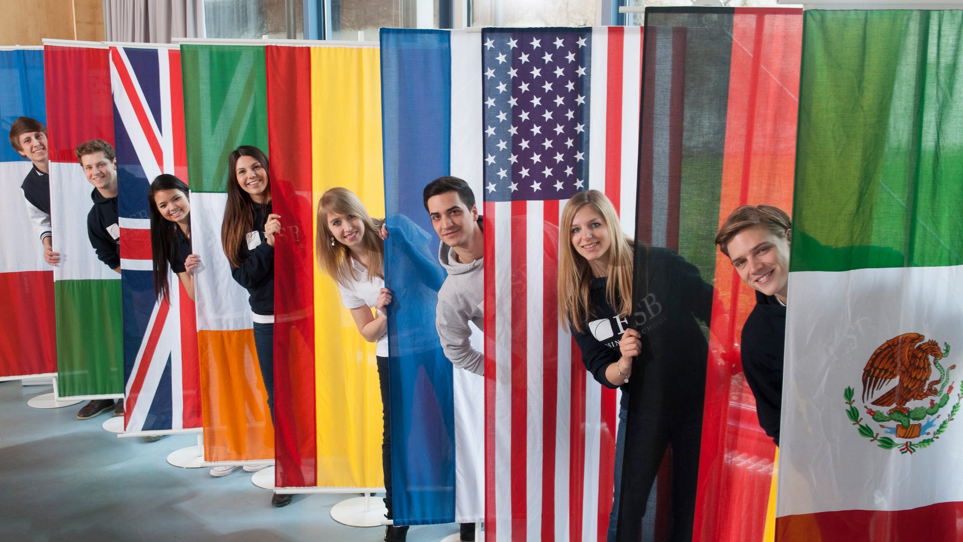 Students posing behind the flags of countries of the partner universities of ESB Business School.